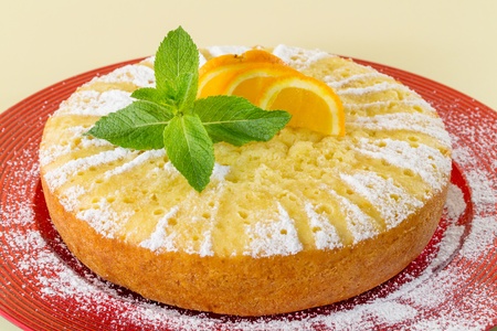 Home made whole testy orange cake, on red plateの写真素材