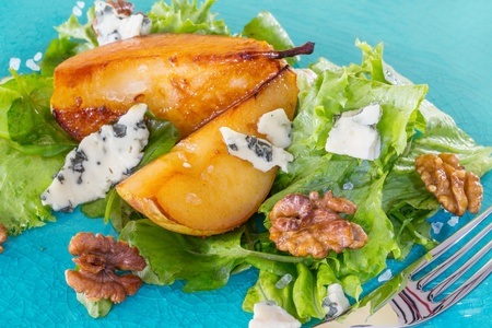 Salad with caramelised pears, walnuts and cheese on blue lateの写真素材