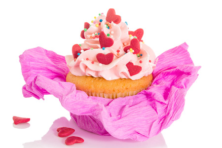Vanilla cupcake with pink frosting and pink cup, decorated with red hearts, isolated on white background の写真素材