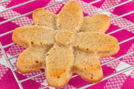Homemade muffin in the shape of flower  on cooling rack ad pink backgroundの写真素材