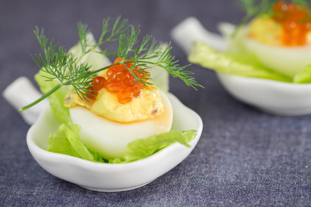 Staffed egg appetizer with red caviar garnish and dill decorationの写真素材