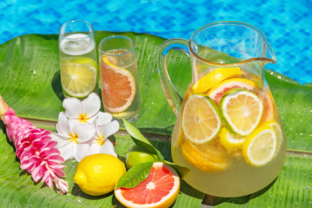 Jug of home made iced lemonade on edge of swimming poolの写真素材