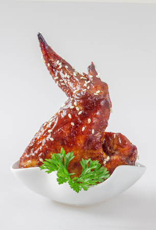 Single BBQ chicken wing in small  white bowl, on white backgroundの写真素材
