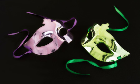 Purple and green carnival mask on dark background の写真素材