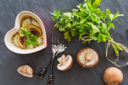 mushroom casserole in heart shape  with fresh parsley and cheese on gray stone background, top viewの写真素材