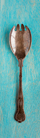Old serving fork on blue background vertical composition top viewの写真素材