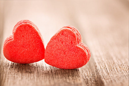 Two red heart shaped cookies, extreme close up, selective focus, on wooden backgroundの写真素材