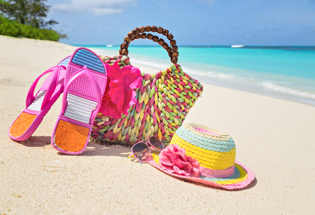 Bag, hat, flip-flops and sunglasses on sunny beach, tropical beach vacation and travel conceptの写真素材