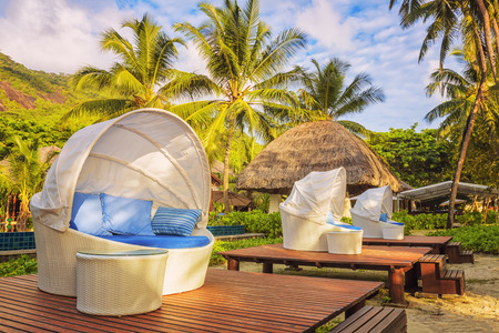 Nice cozy white round chairs with canopy and blue cushions on beautiful tropical resort backgroundのeditorial素材