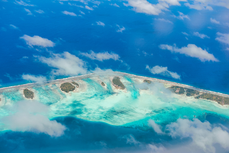 Aerial view of the island with clouds, reef and lagoon. Island near Tahiti in the tropical archipelago of French Polynesia inside the Pacific ocean.の写真素材