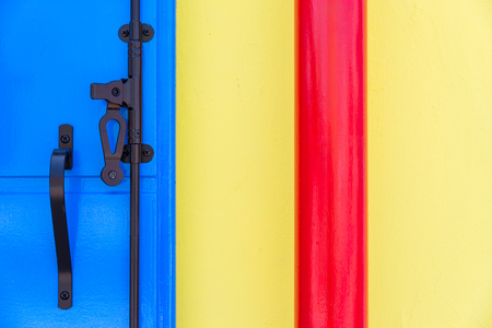 Yellow, blue and red part of the wall with black metal elementの写真素材