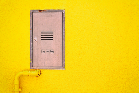 Gas pipe and a manhole in a bright yellow wall