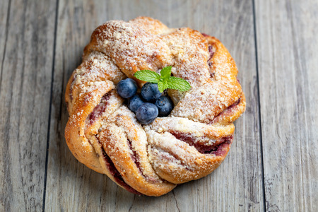 Blueberry pleated bun with powdered sugar and fresh berries o wooden background