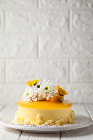 Mango cheesecake with yellow jelly topping, with flowers and fresh mango pieces on white backgroundの写真素材
