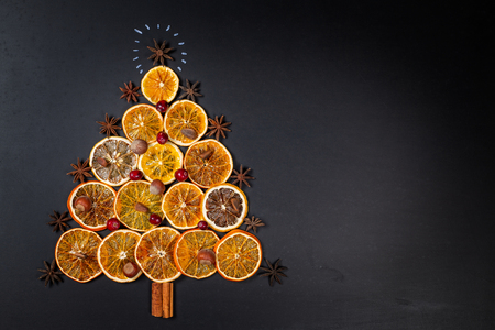 Christmas tree made of dried oranges, cinnamon and star anise on dark background.の写真素材