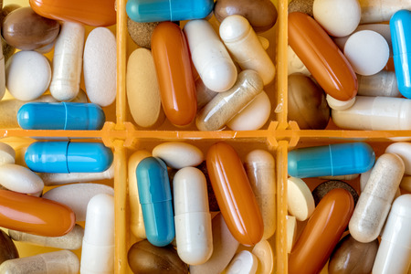 Background of close up orange medical container with different type and colour pills