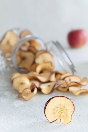 Dried apples chips in glass jar on light background, vertical composition - Imageの写真素材