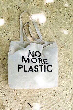 Eco bag with No More Plastic concept sign on topical beach sand, top viewの写真素材