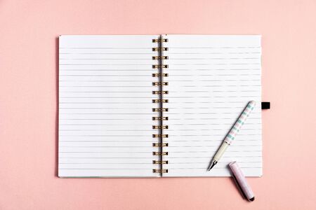 Top view of blank notebook with pen on pink pastel backgroundの写真素材