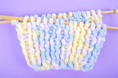 Handicraft needlework concept - hand-knitted item with knitting needles and thread in heart shape on...