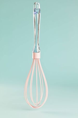 Single Pink silicone whisk on light blue background, vertical composition の写真素材