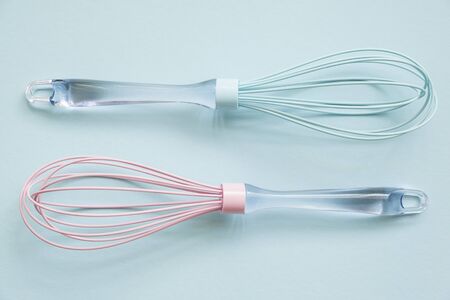 Pink and blue silicone whisks  with clear handle  on blue background, tp vuew 