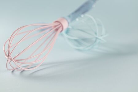 Blue and Pink silicone whisk  with clear handle  on blue background with copy spaceの写真素材