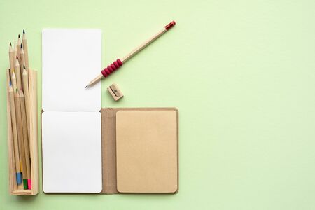 Environmentally friendly  Eco concept of notepad, pencils, sharpener on green background, top view, copy space の写真素材