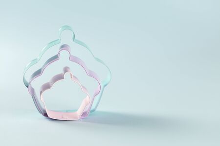 Three metal cookie cuter standing on light blue background, with copy space