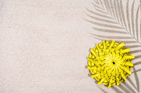 Hand made yellow palm tree leafâs hat on sand with palm shadowの写真素材