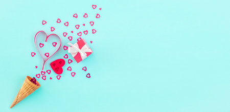 Ice-cream cone with heart shaped  decoration and small red present box on blue background,...