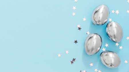 Easter silver eggs and small silver stars on blue background with copyspace. Beautiful easter cardの写真素材