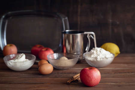 Large red apple with cinnamon sticks and basic  ingredients for cooking apple pie on dark  wooden brown backgroundの写真素材