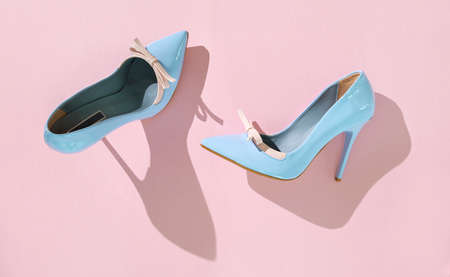 Pare of light blue high heel shoes on pink background, flat lay with copy space