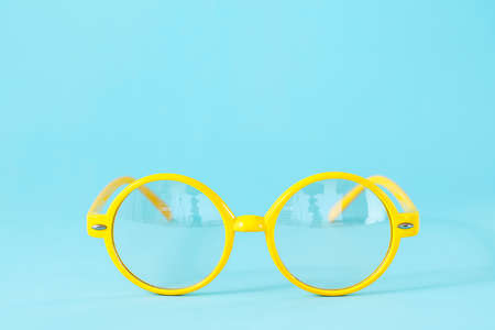 Round yellow glasses on light blue background with copy space