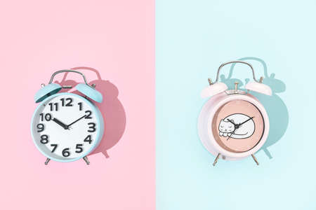 Old fashion blue and pink alarm clock on pink and blue background, flat lay with copy spaceの写真素材