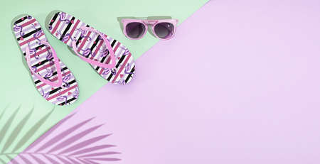 A pair of summer sandals, flip flop and pink sunglasses on pastel pink and green background with palm leaf shadow, top view, copy spaceの写真素材