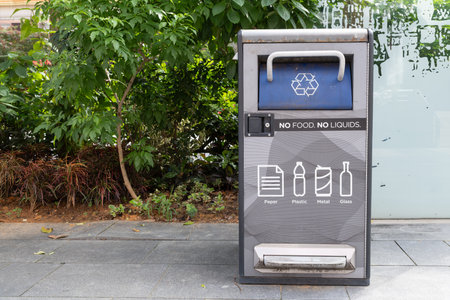 Singapore, Singapore - May 01, 2025: A recycling bin located on Orchard Road in Singapore, featuring clear instructions for waste disposal, surrounded by lush greenery and urban elementsの写真素材