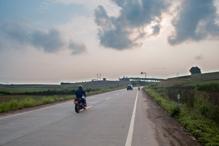Rear view of a motorcyclist riding a motorbike on the road.の写真素材