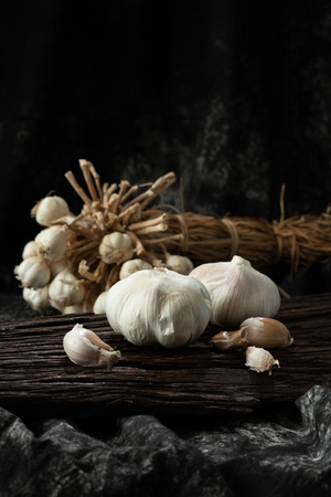 garlic cloves and bulb on vintage wood black clothの写真素材