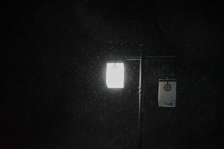 Street lights under snowflakes at nightの写真素材