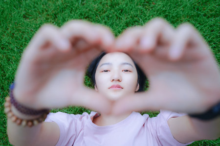 Girls lying on the lawn to compare heartsの写真素材