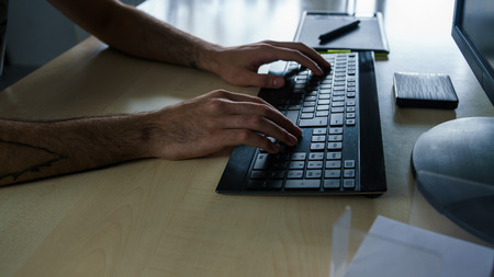 Hands pushing Keys with Graphic Tablet in Backgroundの写真素材