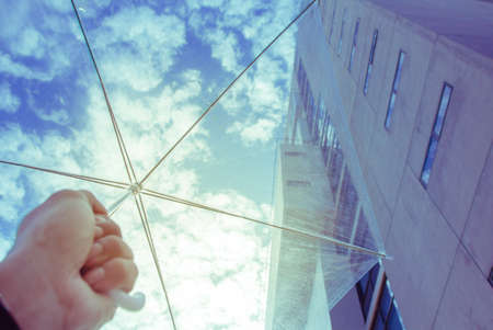 Clear plastic umbrella on hand  a blue sky background