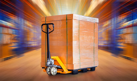 Package Boxes with Hand Pallet Truck in Blurred Warehouse Space. Forklift Loader. Storage Warehouse. Supply Chain Supplies Shipment Goods. Distribution Shipping Warehouse Logisticsの写真素材