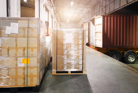 Package Boxes Wrapped Plastic Stacked on Pallets. Trucks Loading Goods at Warehouse Port at Night....