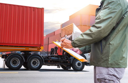 Workers Holding Clipboard Inspects Container Trucks. Control the Loading of Goods at the Port Warehouse. Distribution Warehouse. Shipping Cargo Container. Freight Truck Logisticsの写真素材