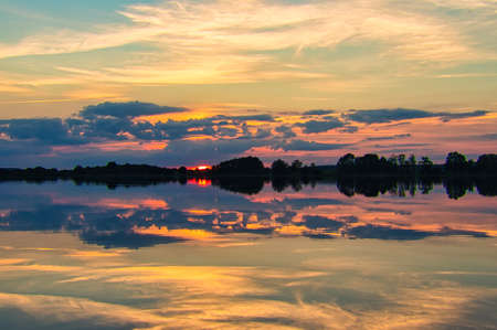 reflection of the sky in the water. gold, yellow and pink colors of the sky are reflected in the...