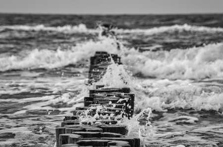 groynes on the beach of the Baltic Sea in Zingst. Waves break on the wood. they protect the coast of the German Baltic Sea from the waves. In addition, they are also beautiful to look at.の写真素材