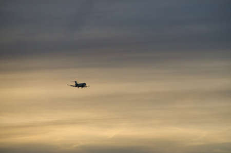 airplane in the evening sky in luminous horizon. vacation trip or cargo transport.の写真素材